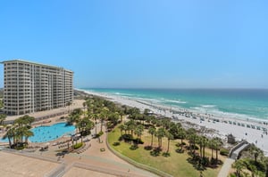 Beachfront resort with swimming pool and pristine white sand beach stretching along emerald Gulf waters.