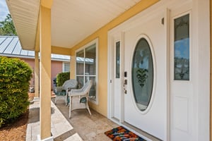 Welcoming entrance with elegant glass door and cozy patio seating where you can relax and enjoy your morning coffee.