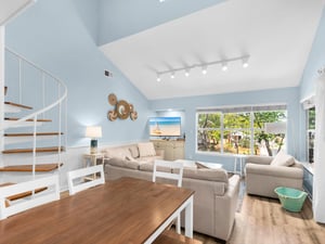 Relax in your bright living room with cozy seating, entertainment center, and beautiful garden views through large windows.