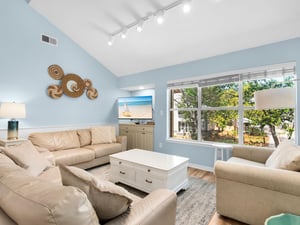 Unwind in your bright living room with vaulted ceilings, comfortable seating, and peaceful garden views through oversized windows.