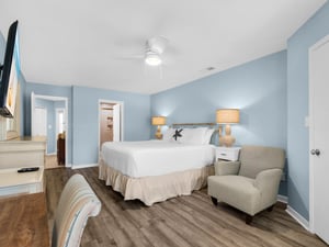 Unwind in your serene coastal bedroom with soft blue walls, plush king bed, and cozy seating area perfect for morning coffee or evening relaxation.