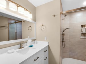 Step into your modern bathroom featuring a sleek vanity, spacious walkin shower, and plenty of fresh towels for your comfort.