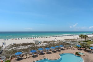 Beachfront resort with pristine white sand, turquoise waters, and pool area overlooking the Gulf Coast.