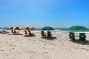 Sandy beach with colorful umbrellas and chairs set up along the pristine waterfront.