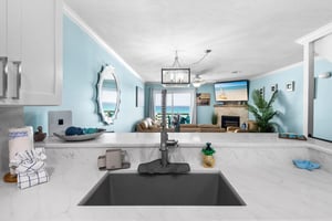The kitchen flows seamlessly into the living area, where ocean views and coastal charm create the perfect backdrop.