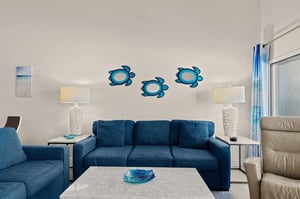 Sink into the plush blue sofa, unwind with a book under the warm glow of elegant lamps, and let the cheerful sea turtle artwork transport you to coastal bliss.