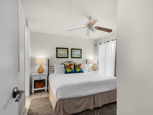 Sink into crisp linens and plush pillows in your private bedroom. A ceiling fan keeps you cool, while warm lamps and coastal artwork create a relaxing retreat after a day of adventure.