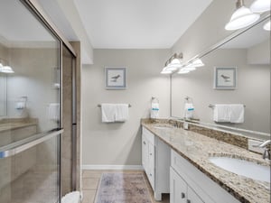 Coastalinspired bathroom featuring a walkin shower and dual vanity. Soft lighting and fresh towels await after your day exploring.