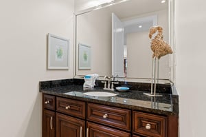 Half bathroom located just off the kitchen area, with granite countertops and warm wood cabinetry.