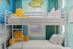 Beachthemed bunk room awaits with cheerful yellow pillows, and playful ocean artwork