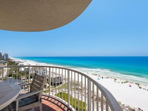 A curved balcony overlooks a pristine white sand beach and turquoise Gulf waters, offering an elevated coastal perspective for arrival at this beachfront property.