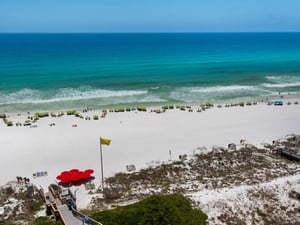 This stunning beachfront property offers direct access to pristine white sand and turquoise Gulf waters. Guests enjoy a spacious beach area with umbrellas and loungers.