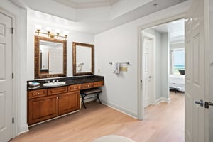 The Primary bathroom vanity features rich wood cabinetry, granite countertops, and elegant framed mirrors—perfect for refreshing each morning.