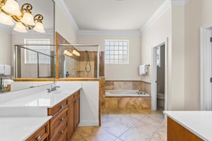 Unwind in the spacious primary bathroom featuring a soaking tub, walkin shower, dual vanities, and warm natural light streaming through frosted windows.