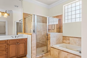 The primary bathroom features a spacious walkin shower and a relaxing soaking tub, bathed in natural light from a charming gridded window.