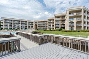 Threestory property features tiered architecture with multiple balconies, manicured lawn, swimming pool, and waterfront access via private boardwalks.