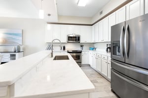 Your fully equipped kitchen features gleaming quartz countertops, stainless steel appliances, and bright white cabinetry—perfect for preparing everything from quick breakfasts to memorable vacation di