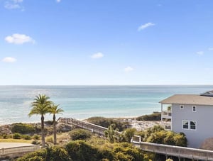 Coastal property featuring direct beach access via boardwalk, tropical landscaping, and stunning ocean views in a serene beachfront community.