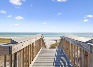 Private boardwalk leads directly to pristine white sand beach and crystalclear turquoise waters under sunny skies, offering easy access to your coastal escape.