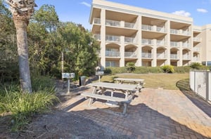 The property building features balconies overlooking lush tropical landscaping and a convenient picnic area with shaded seating—perfect for outdoor relaxation.