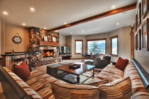 Second living room with expansive southwestern upholstered sectional, gas burning fireplace with stone surround, and TV.