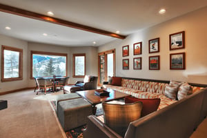 Second living room with Utah art prints, large windows, sectional and accent chair, and round game table with comfy chairs.