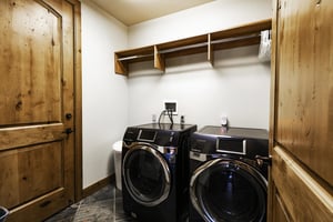 First set of front loading washer and dryer in a black color with storage above there is a second set on a different floor.