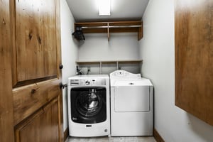 Second set of front loading washerdryer in white color with storage above.