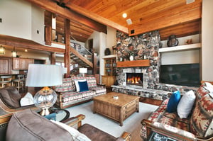 Living room with southwestern upholstered couches, suede accent chairs, and wood burning fireplace with stone hearth.