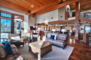 Solid wood coffee table in the living room with upholstered couches, 2 chairs, cream walls, and hard wood floors and ceiling.