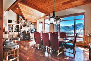 Solid wood dining room table with red high back upholstered dining chairs and mountain views from the large picture windows.