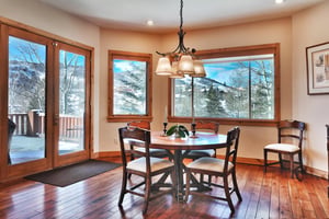 Quaint breakfast nook off the kitchen with a round table and seating for four, wood floors, and panoramic mountain views.