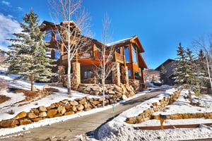 Thistle Home exterior with large flagstone and wood beams, private decks, striking windows and stone lined driveway.