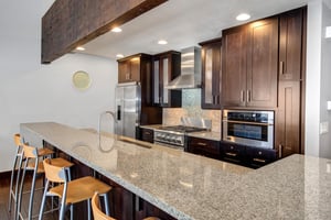 The wellequipped kitchen has dark wood cabinets, stainless steel appliances and island.