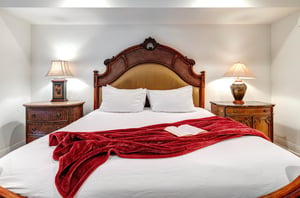 The main suite offers crisp white linens and red throw blanket on a king size bed.