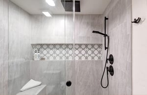 The en suite bathroom offers a spalike shower, where a dual rainfall and handheld system meets elegant mosaic tile.