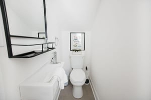 Just between the living room, and the kitchen, a half bath has been tucked beneath the staircase.