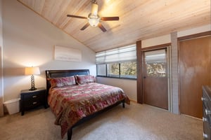 Rest easy in the spacious king master bedroom at Park Avenue 235, featuring vaulted wood ceilings, a ceiling fan, and peaceful natural light.