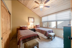 The second bedroom at Park Avenue 235 features two twin beds, vaulted ceilings, and a ceiling fan — ideal for kids, friends, or extra guests.