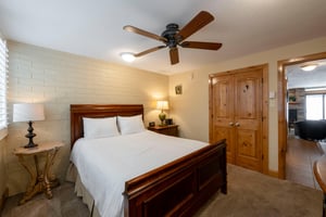 A queen bed, ceiling fan, inroom TV, and abundant natural light make the bedroom at Park Avenue 211 a bright and comfortable retreat.