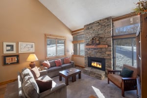 Cozy up by the stone gas fireplace in the living room at Park Avenue 224 — the perfect spot to unwind after a day on the slopes.