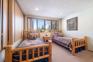 The charming twin bedroom at Park Avenue 243 features rustic logframe beds and bright natural light, making it the perfect space for younger guests at this familyfriendly Park City condo rental.