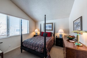 The classic and comfortable bedroom at Park Avenue 251 features an elegant fourposter bed, vaulted ceilings, and plenty of natural light — a restful haven within this wellappointed Park City condo 