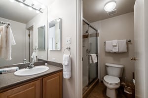 The clean and wellappointed bathroom at Park Avenue 251 features a sleek glassenclosed shower, warm wood vanity, and all the essentials for a comfortable and convenient Park City condo rental stay.