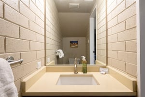 The sleek and stylish main level half bathroom at Park Avenue 256 features a cleanlined vanity, warm tile walls, and modern finishes — a thoughtful and convenient touch that enhances this premier Par