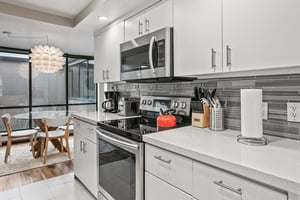 The fully equipped modern kitchen at Park Avenue 296 features stainless steel appliances, crisp white cabinetry, and elegant tile backsplash. Everything you need to cook and entertain during your Park