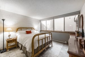 Rest and recharge in the bright and charming primary bedroom at Park Avenue 297. With a classic iron bed frame, crisp white linens, and plenty of natural light, this peaceful retreat makes this Park C