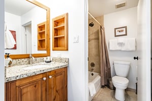 The shared bathroom at Park Avenue 333 is wellappointed with warm wood cabinetry, granite countertops, and a tubshower combo — everything guests need for a comfortable and convenient stay at this Pa