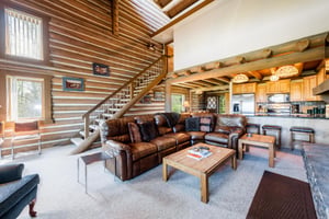 Spacious, stunning, and full of character, the open living area at Temptation 8 features authentic log walls, a grand staircase, and comfortable leather seating — making this Park City lodging destina