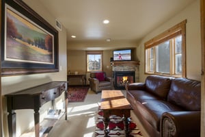Settle into the cozy living room at Jupiter Inn 10, featuring a fireplace, flatscreen TV, and comfortable leather seating. The perfect Park City vacation rental for relaxing after a day on the mounta